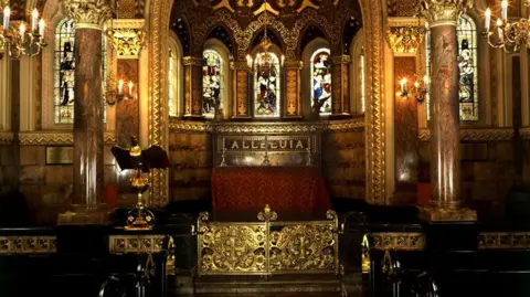 A richly furnished interior of a chapel, with marble pillars and stained glass windows. 