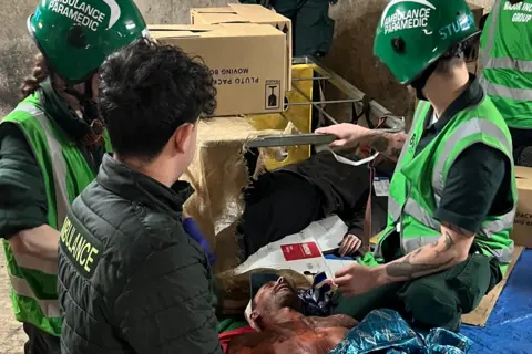 BU One patient - potentially a burns victim - is looked at by three paramedics.