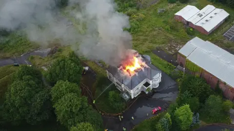 Luke O'Reilly An aerial view of the old Foyle College building. There are flames and smoke coming from the roof. 