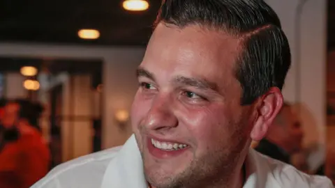 A close up of a smiling man looking to the side