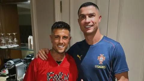 A man in a red t-shirt stood next to a man in a blue t-shirt