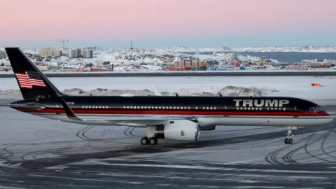 Reuters A red, white and blue plane with 'Trump' written on it is parked on a snowy runway.