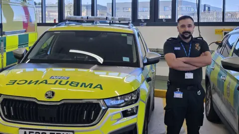 Handout Zain Kazmi at work as an Accident and Emergency operational team leader for Yorkshire Ambulance Service, stood next to an emergency vehicle.