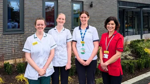 Four health professionals standing outside a clinic.
