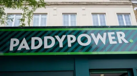 Getty Images Green and white Paddy Power logo in block capitals against a striped background at a betting shop.
