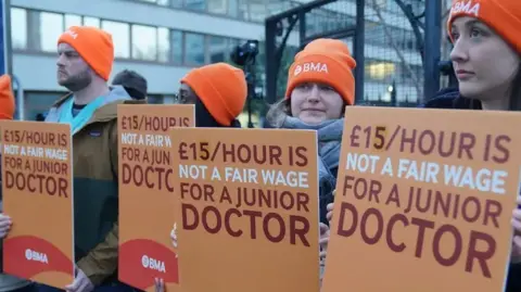 PA Doctors manning a picket line carrying signs saying '£15 an hour is not a fair wage for a junior doctor'