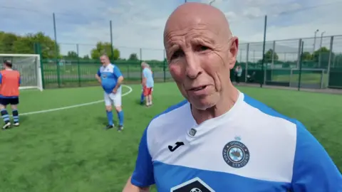 David Muskett on a football pitch with a blue and white football strip and with other players in the background