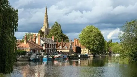 Dr Syntax View of old buildings and a church spire from across the river at Abingdon