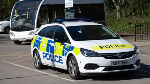 Supplied A police car parked in a bay of a car park. In the background is a white minibus
