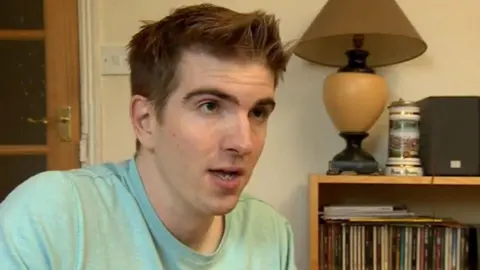 A man sat inside a home giving an interview