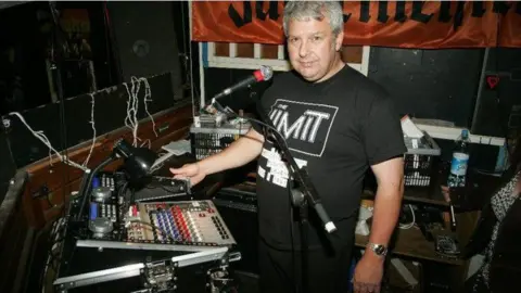 Paul Unwin DJ and manager Paul Unwin DJing at The Limit, wearing a black tdhirt behind some mixing decks 