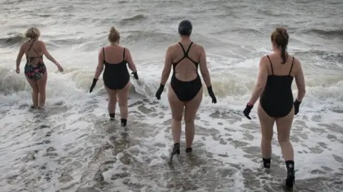 BBC Four women walk into choppy sea waters.