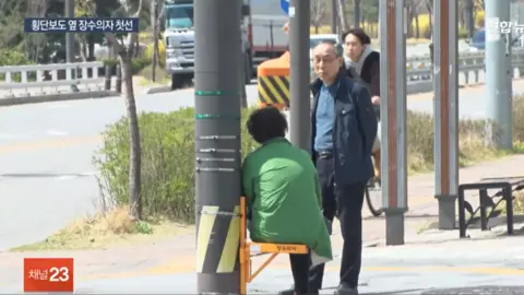 Yonhap News TV/YouTube Chair for older pedestrians to rest at road crossings, Namyangju, South Korea