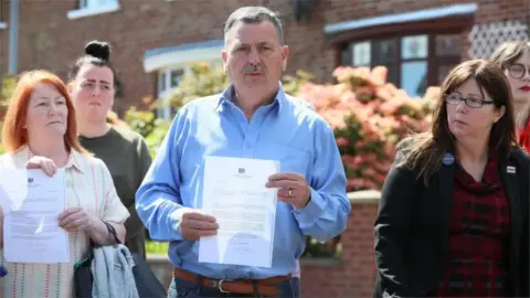 PA Media John Teggart and other Ballymurphy families holding Boris Johnson's letter