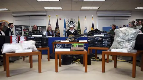 AFP Donald Trump speaks in front of displays of weapons, cash and drugs during a roundtable discussion at the US Border Patrol Station near the US-Mexico border in McAllen, Texas, 10 January 2019