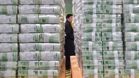 Reuters Bundles of South Korean bank notes for release are stacked as a security worker is seen in the basement of the central bank in Seoul.