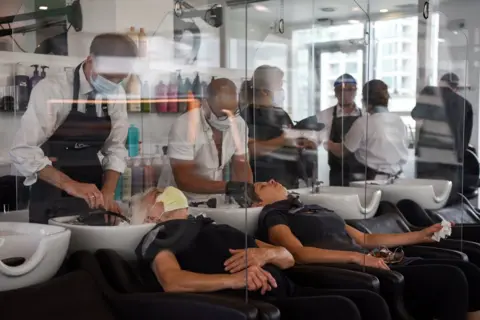 Reuters Women lean back to have their hair washed with plastic barriers dividing each customer