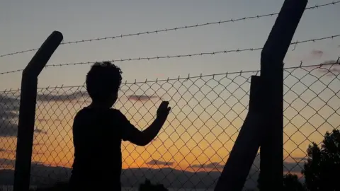 Getty Images Man Standing By Fence Against Sky During Sunset - stock photo