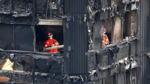 Getty Images Members of the emergency services work on the middle floors of the charred remains of the Grenfell Tower block in 2017