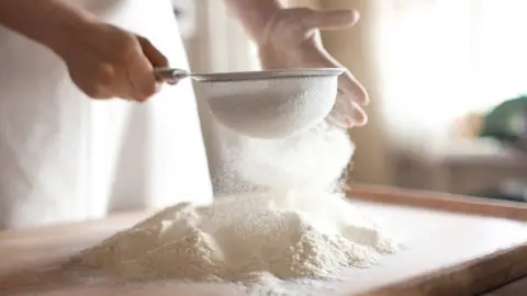 Getty Images Person sifting flour