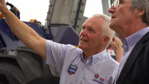 Helen Cowan Geoff in a blue RNLI shirt is talking to a man with glasses