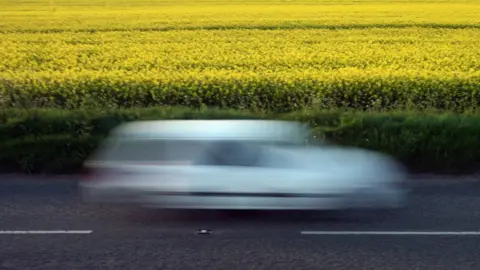 Getty Images car going past oilseed rape plant field