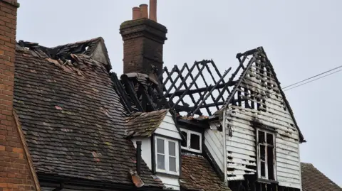 Stuart Woodward/BBC Part of a roof of an old pub. The roof has collapsed on one side, with only charred joists remaining