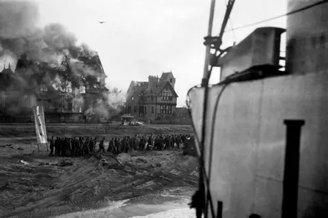 Getty Images A German bomber in action on D-Day, as German prisoners are moved from Juno beach