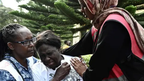 AFP Grieving woman comforted after identifying the body of a relative