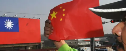 AFP An anti-China protester holds the national flag of China during a demonstration outside of the Windsor hotel, where a fresh round of talks between Taiwan and China talks was being held in the central Taichung city on December 22, 2009. In the bacground was a huge national flag of Taiwan.