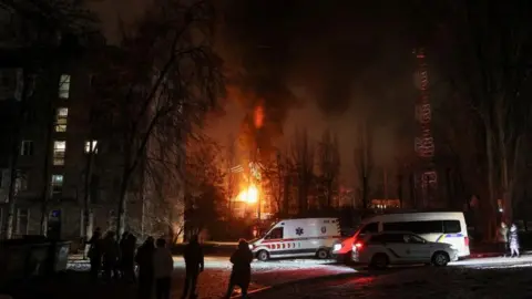 Reuters Local residents gather near a residential building as a critical power infrastructure object burns after a Russian drone attack, amid Russia's attack on Ukraine, in Kyiv, Ukraine December 19, 2022.