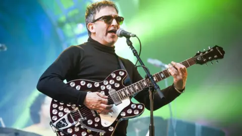 PA Media Ian Broudie of the Lightning Seeds with guitar