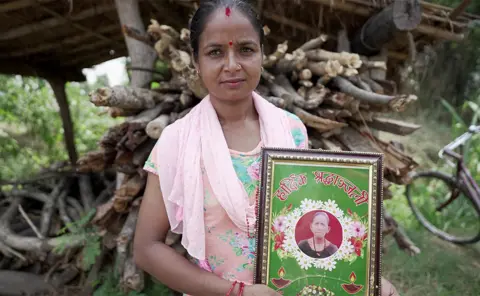 Kevin Kim/BBC Samjhana holds a photo of her mother-in-law