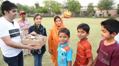 Zymal handing out ice cream to young boys