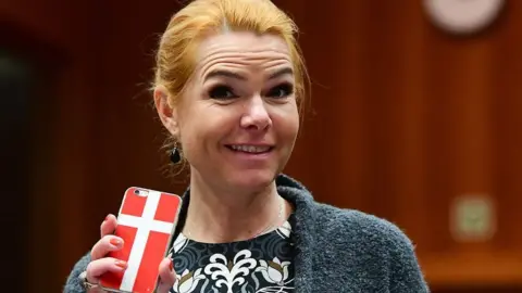 Getty Images Then-Interior Minister Inger Stojberg holds her phone showing a Danish flags in November 18, 2016