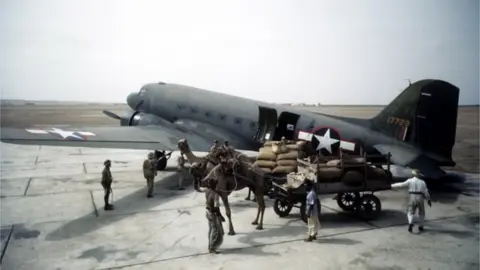 Getty Images Local workers unload a Douglas Dakota Transport airplane at the U.S. Army Air Force Base in Karachi,India.