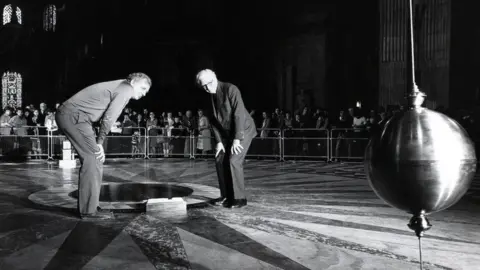 The Open University  The Open University and BBC reconstruct the famous Foucault experiment, which proved the earth goes around the sun, by hanging a brass ball 300ft from the roof of St Paul’s Cathedral in London.