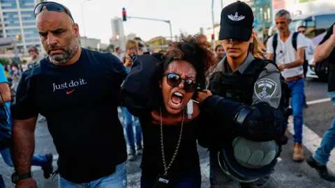 AHMAD GHARABLI Members of the Israeli security forces detain a protester during a demonstration in Tel Aviv on July 3, 2019, against police violence and the recent killing of a young man. - Israel braced for a third day of protests after an off-duty police officer killed a young man of Ethiopian origin, as Israeli leaders urged calm amid accusations of racism. In areas throughout the country since July 1, protesters have blocked roads, burned tyres and denounced what they see as discrimination against the Ethiopian-Israeli community. Police say 136 people have been arrested and 111 officers have been wounded, many injured by stones, bottles and petrol bombs thrown at them.