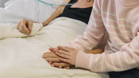 Getty Images Relative holding patient's hand