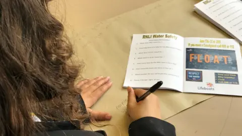 A girl writing on a water safety poster