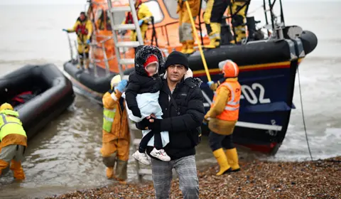 HENRY NICHOLLS Blurred image of a man holding a child after disembarking an RNLI lifeboat at Dungeness on 24 November