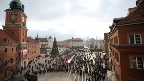 EPA The people of Warsaw watch the funeral on a screen in Castle Square