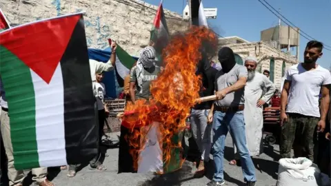 EPA Palestinians burn a UAE flag near Hebron in the West Bank (14/08/20)