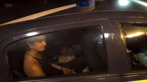 Getty Images Carola Rackete being taken away in a police car following her arrest by Italian police for forcing a ship carrying dozens of migrants into Italian waters