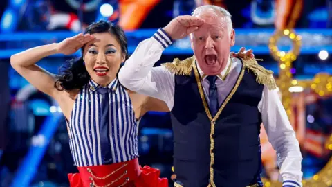 Les Dennis and dance partner Nancy Xu both saluting during a routine on Strictly Come Dancing