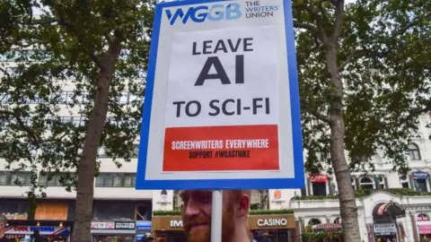 Getty Images A protester holds a placard opposed to AI (Artificial Intelligence) replacing writers, at a protest organised by performing arts union Equity in solidarity striking US screenwriters.