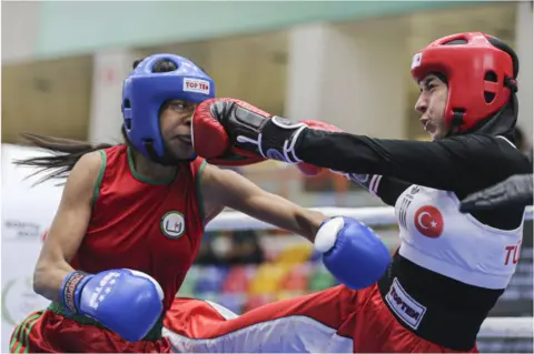 Getty Images Two women punching each other during a boxing match.