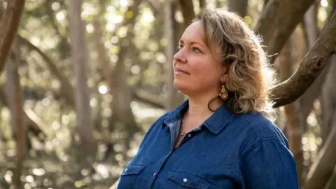 Catherine McLachlan Shannon Foster stands in front of trees