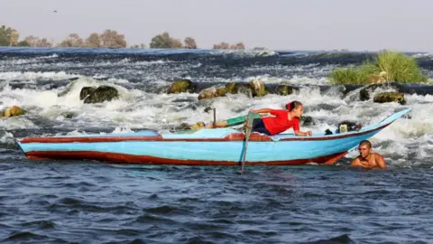 Mohamed Abd El Ghany/ Reuters Person in a boat and another swimming in water, 4 August 2023