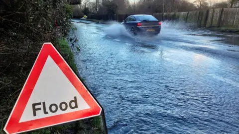 Getty Images A car driving past a flood sign